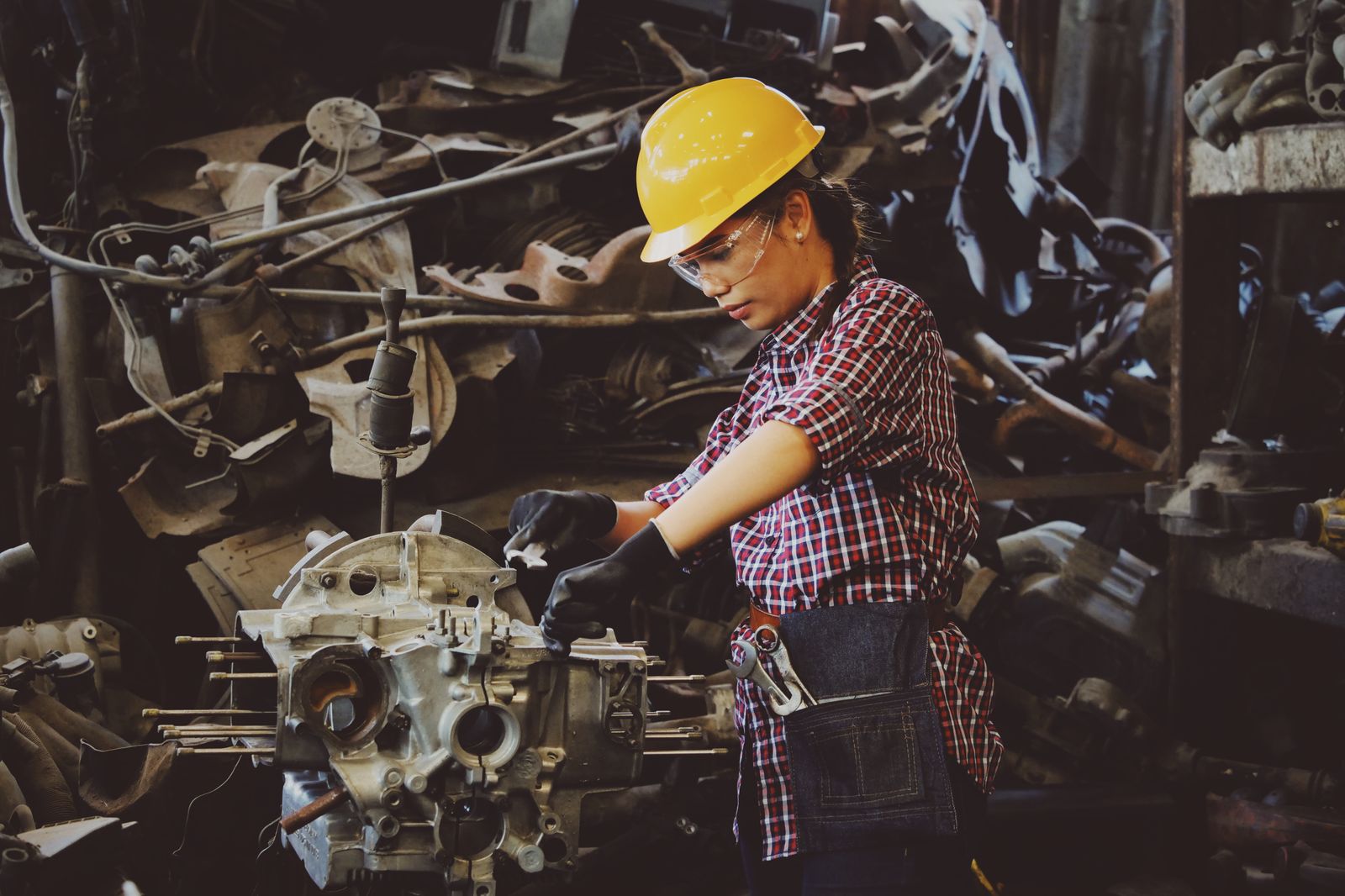 A worker in a hard hat and safety glasses assembling machinery
