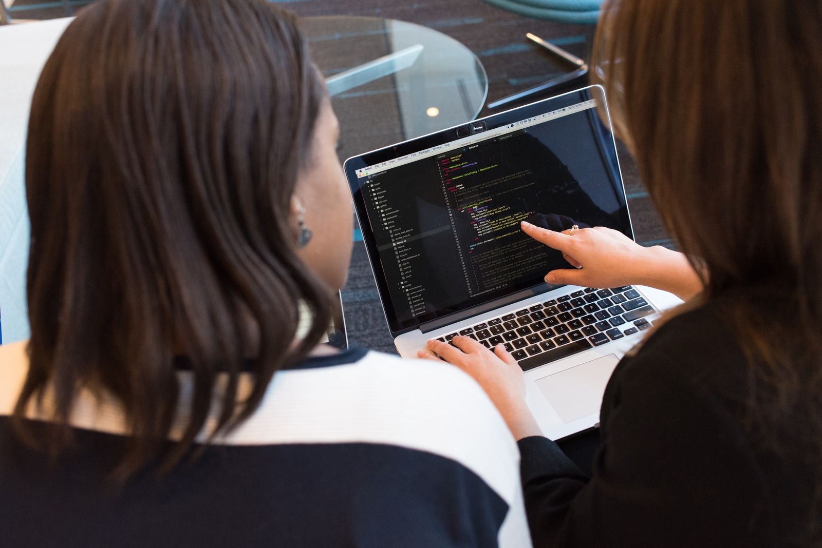 Two colleagues reviewing code together on a laptop