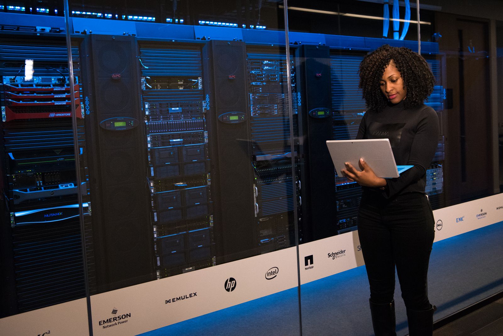 Someone holding a tablet beside server racks behind glass