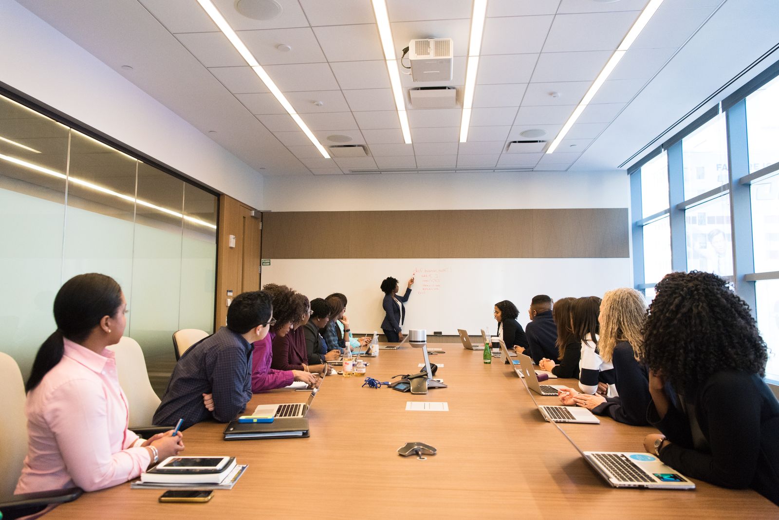 A large meeting with someone writing on a whiteboard