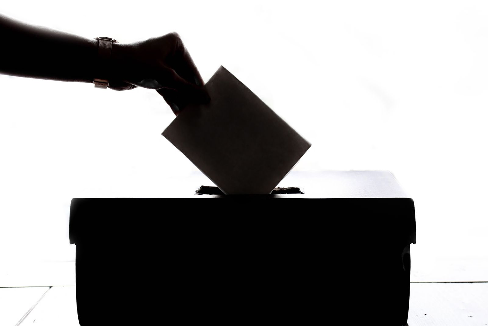 A hand posting a ballot paper into a ballot box
