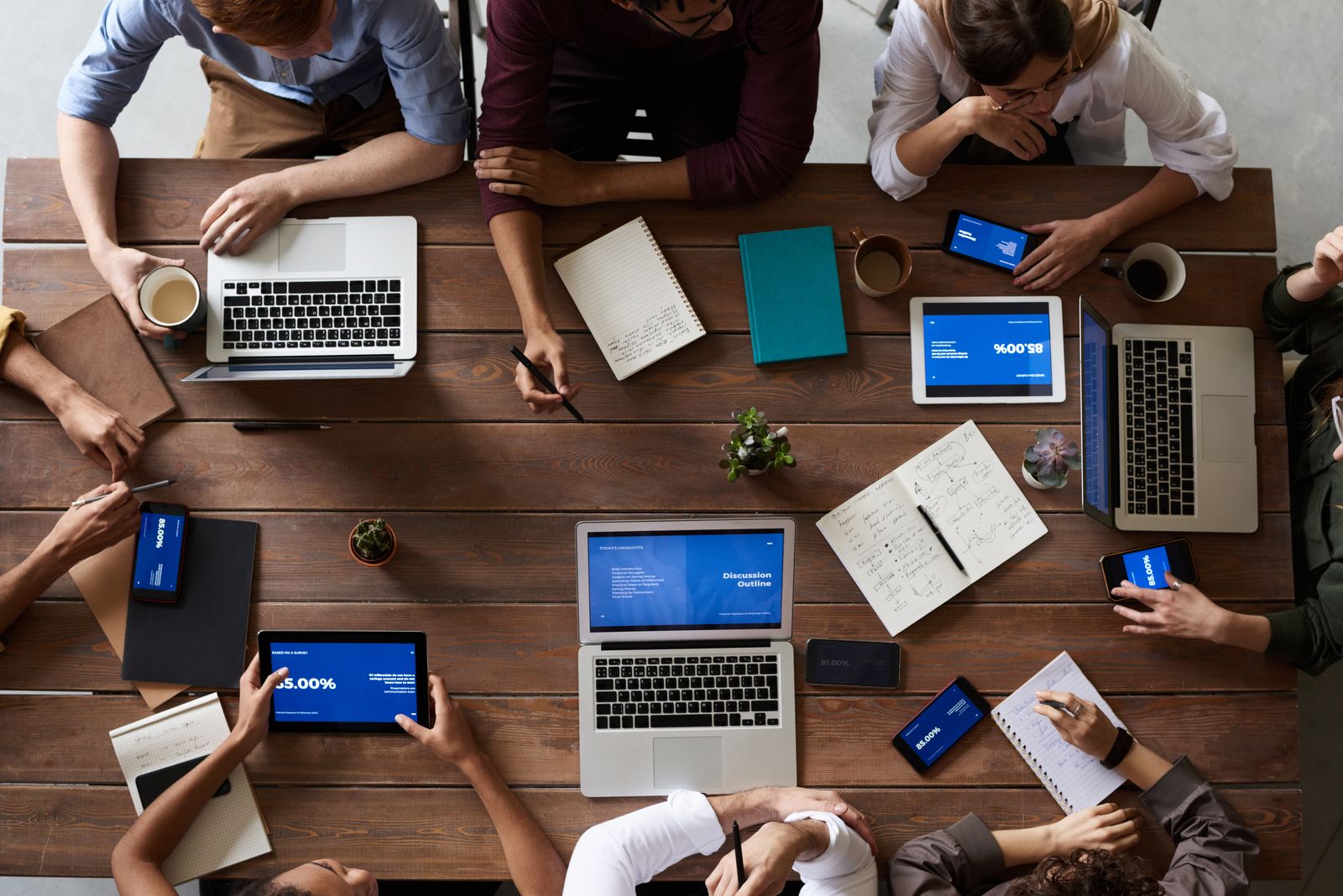 A team meeting seen from above, laptops and tablets across the table