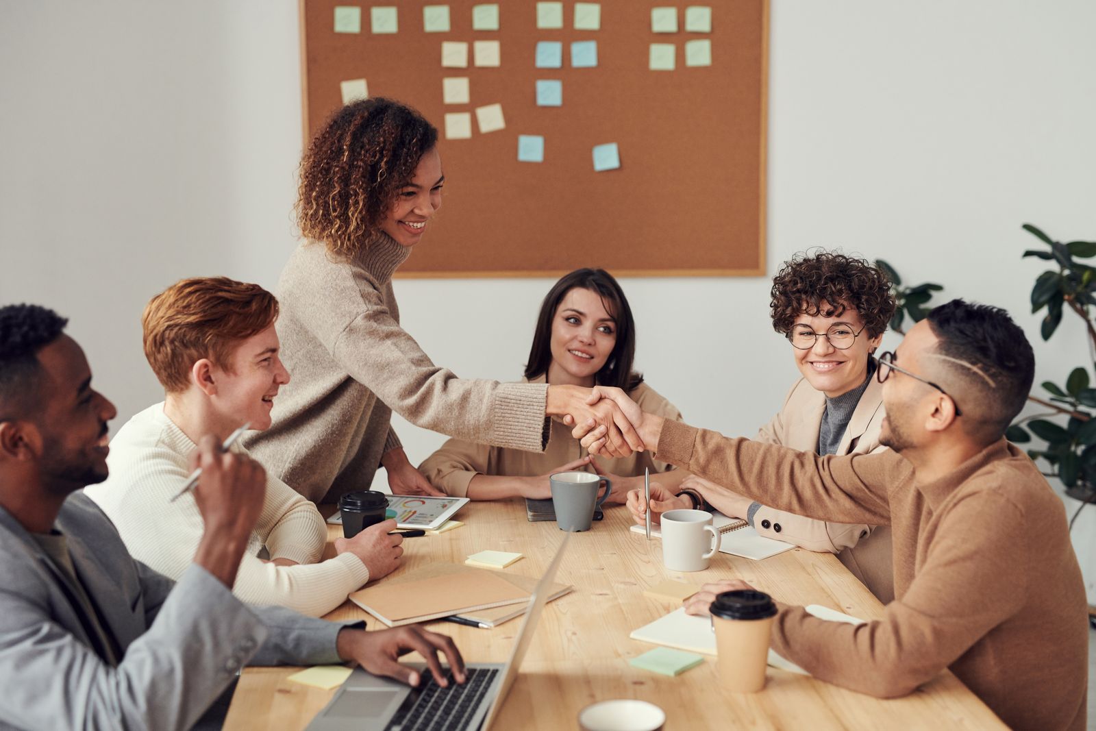 Colleagues at a table, two of them shaking hands