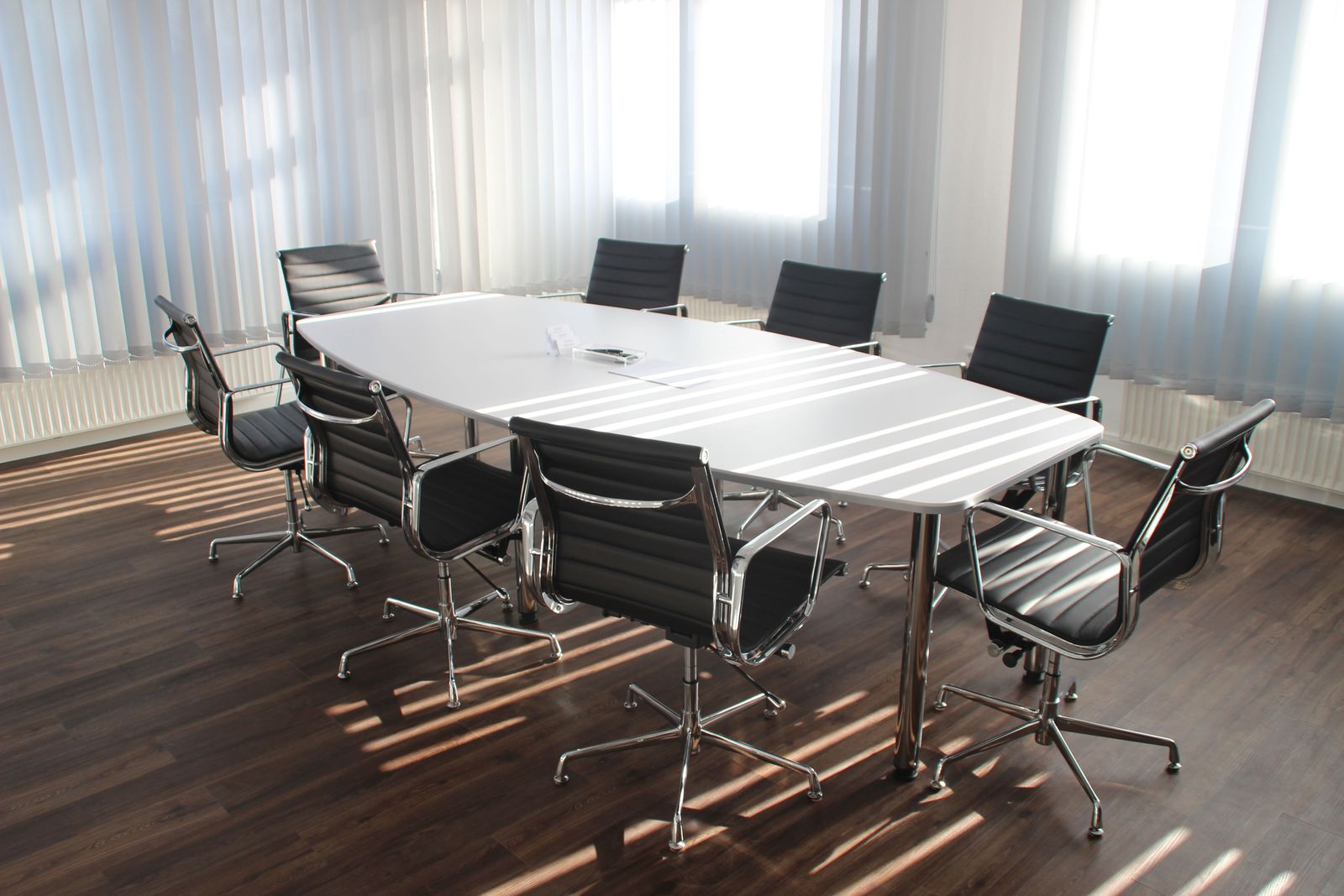 An empty meeting room lit by sunlight through vertical blinds
